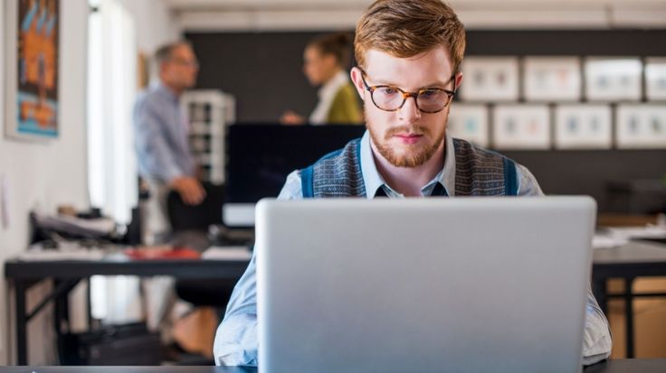 Man working on a laptop, focusing on ad copywriting for Google Ads in an office setting. 